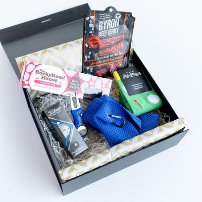 Open gift box for men with golf items socks salami bites in a black box